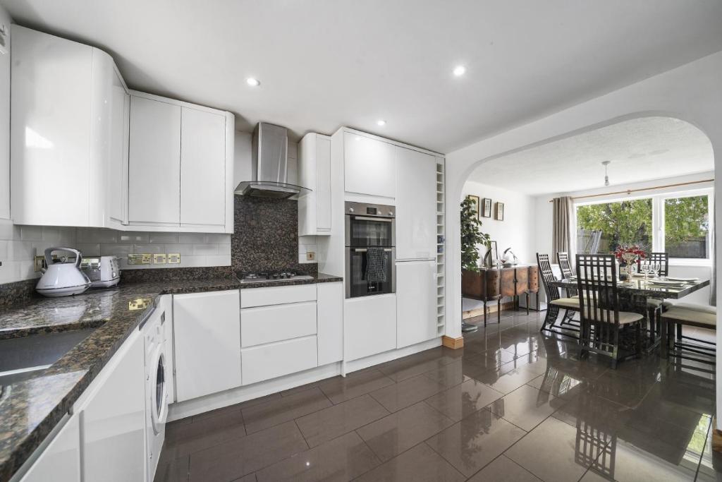 a kitchen with white cabinets and a dining room at Spacious 5-Bed House in Aylesford in Snodland