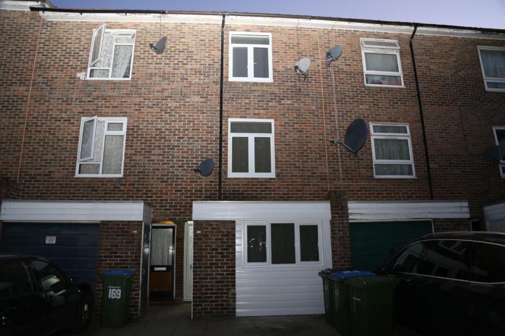 a brick building with white garage doors and windows at Budget 4-Bed House in Woolwich in London