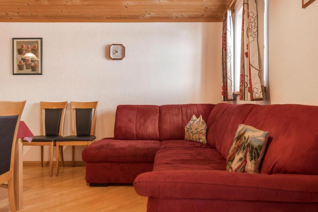 a living room with a red couch and two chairs at Ladinser Hof Reiterstube in Castelrotto