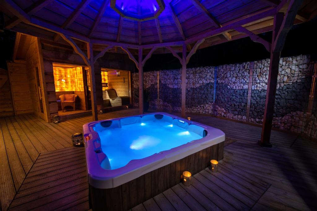 eine Whirlpool-Badewanne in einem Haus mit lila Beleuchtung in der Unterkunft Domaine du Haut Jardin Hôtel & Chalets Spa Privé in Rehaupal