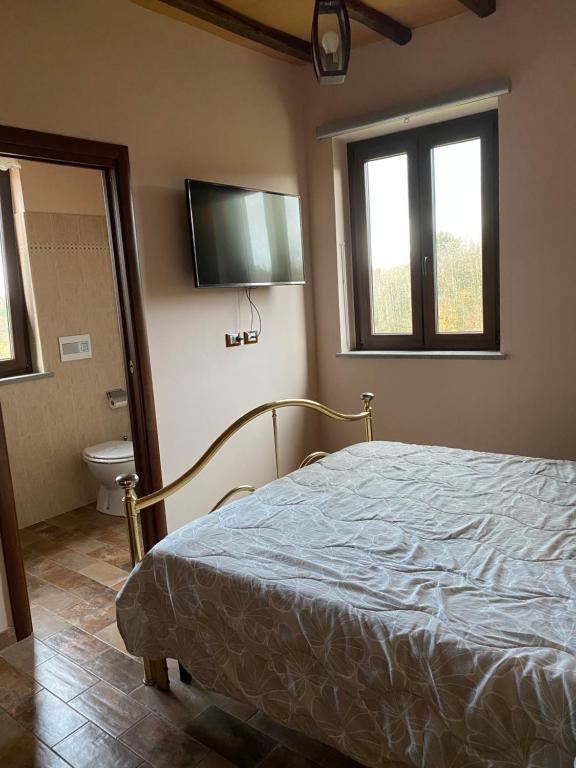 1 dormitorio con cama, aseo y TV en Le case di Nonna Gina en Capranica