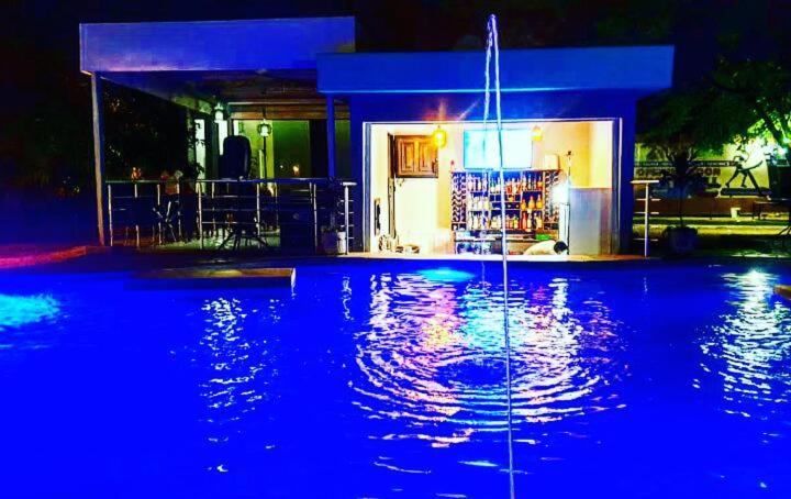 una piscina con luces azules frente a una casa en THE ESCAPE LODGE, en Lusaka