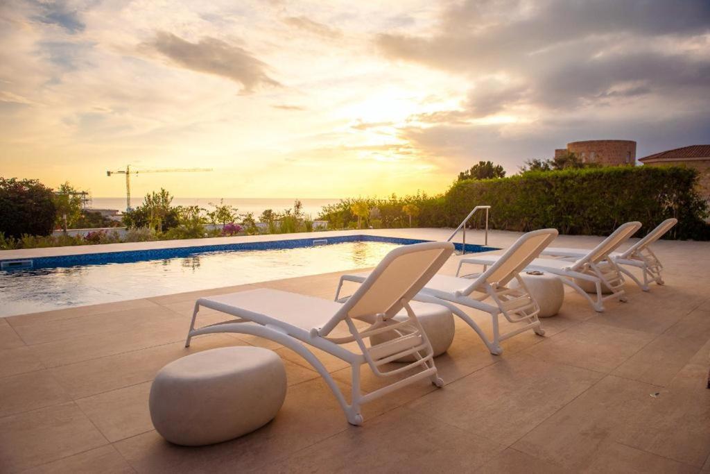 un grupo de sillas sentadas junto a una piscina en Villa No 1 - Cap St Georges Resort, en Peyia
