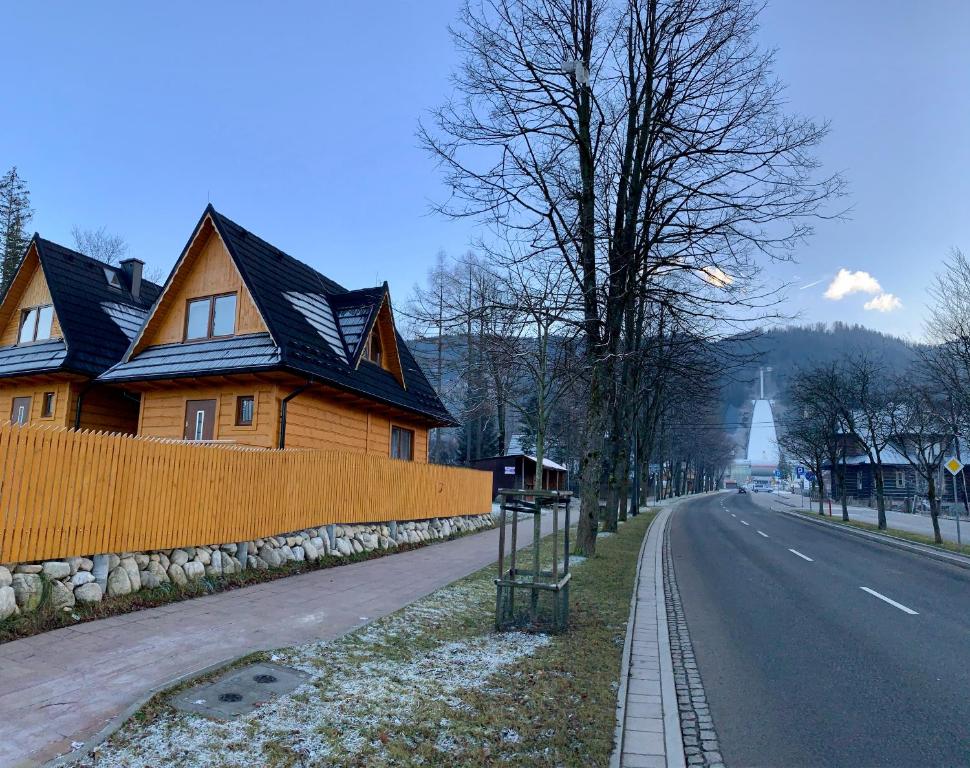 een houten huis aan de kant van een weg bij Domki pod Skocznią in Zakopane