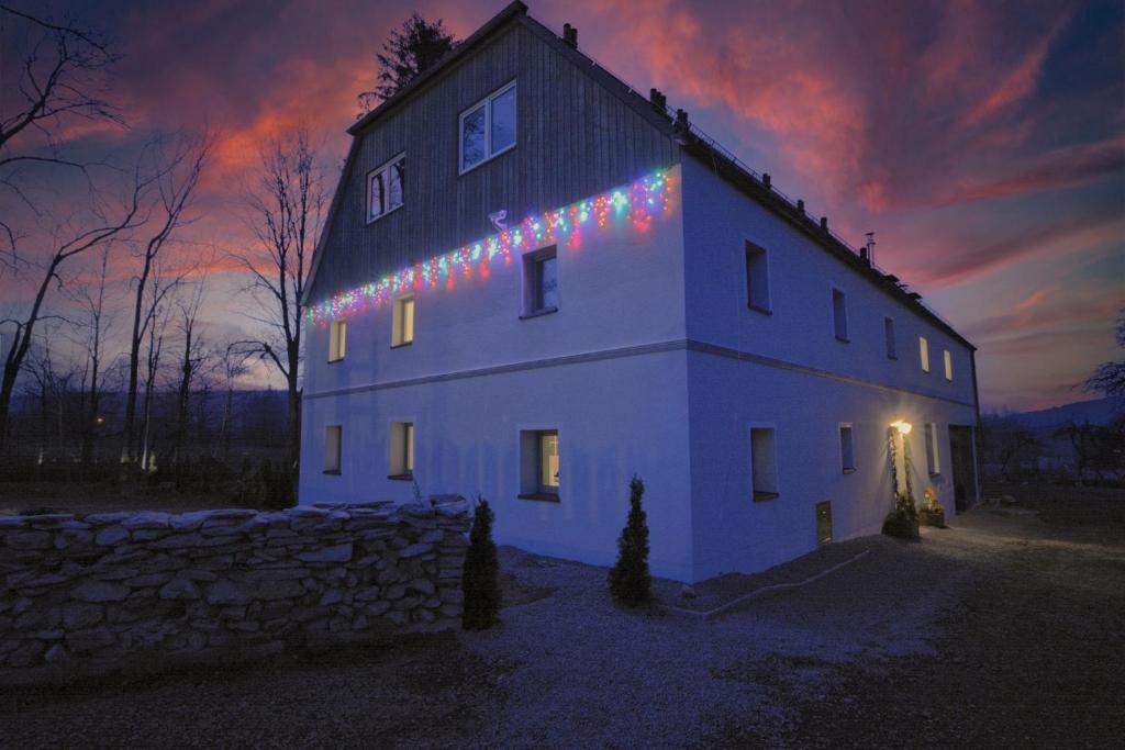 Una casa blanca con luces de Navidad en un lado. en Siedlisko Krasna, en Świeradów-Zdrój