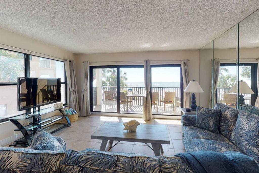 uma sala de estar com um sofá, uma televisão e uma mesa em 101 - Sandy Shores em St. Pete Beach