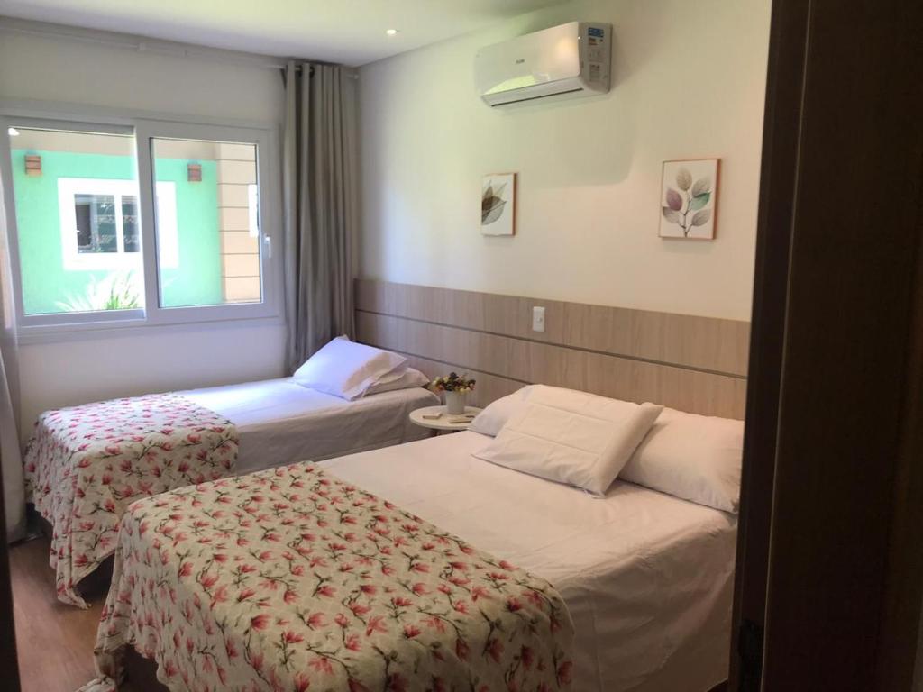 una camera d'albergo con due letti e una finestra di Flat Charme Gramado a Gramado