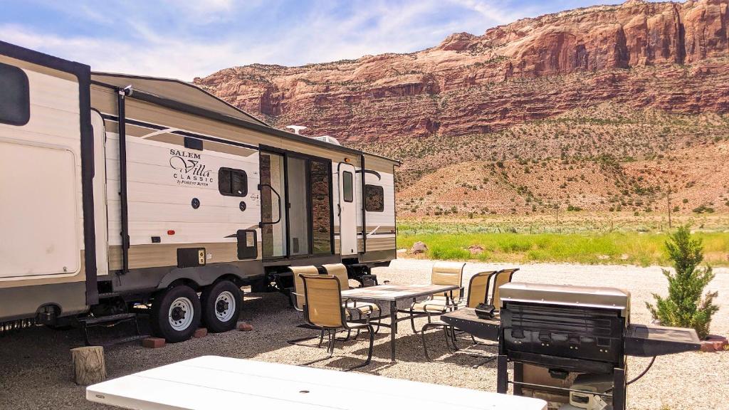 een camper geparkeerd in de woestijn met een tafel en stoelen bij FunStays Glamping Destination RV Site 5 in Moab