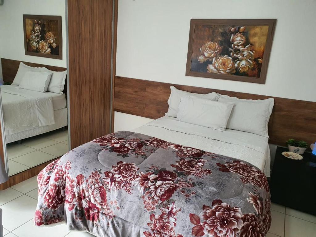 a bedroom with a bed with a floral blanket on it at Flat à Beira Lago in Brasilia