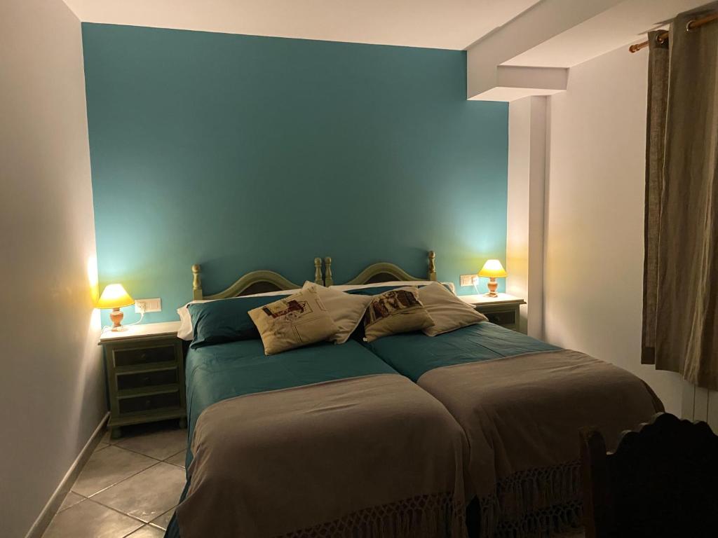1 dormitorio con 1 cama con pared azul en La Fusteria del Casat, en Sarroca de Bellera