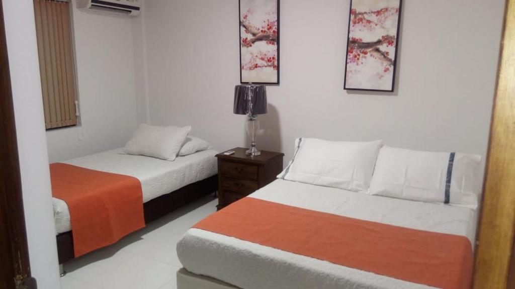 a bedroom with two beds and a night stand with twoitures at Apartamentos Turisticos Doña Flor in San Andrés