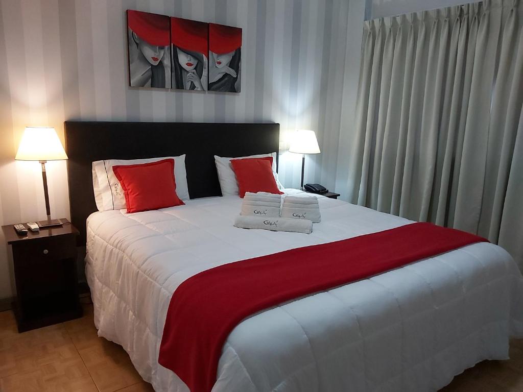 a bedroom with a large bed with red and white pillows at Apart Gala in Mendoza