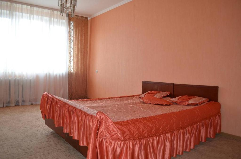 una camera da letto con un letto con un piumone arancione e una finestra di скд46 a Sumy