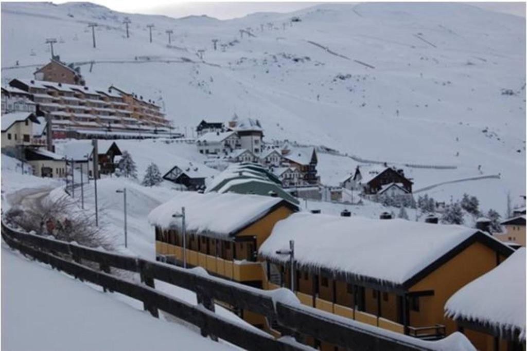 uma estação ferroviária com edifícios cobertos de neve e uma montanha em Sierra Nevada Apartment em Granada