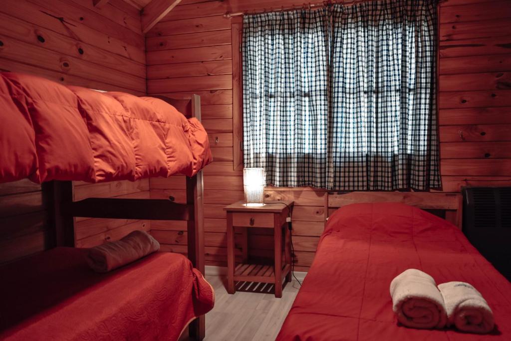 1 dormitorio con 2 camas y una ventana en una cabaña de madera en Cabañas de Troncos en San Martín de los Andes