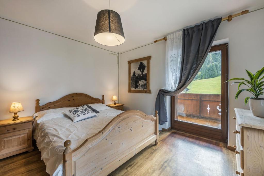 sypialnia z łóżkiem i dużym oknem w obiekcie Agritur Broch w mieście Fiera di Primiero