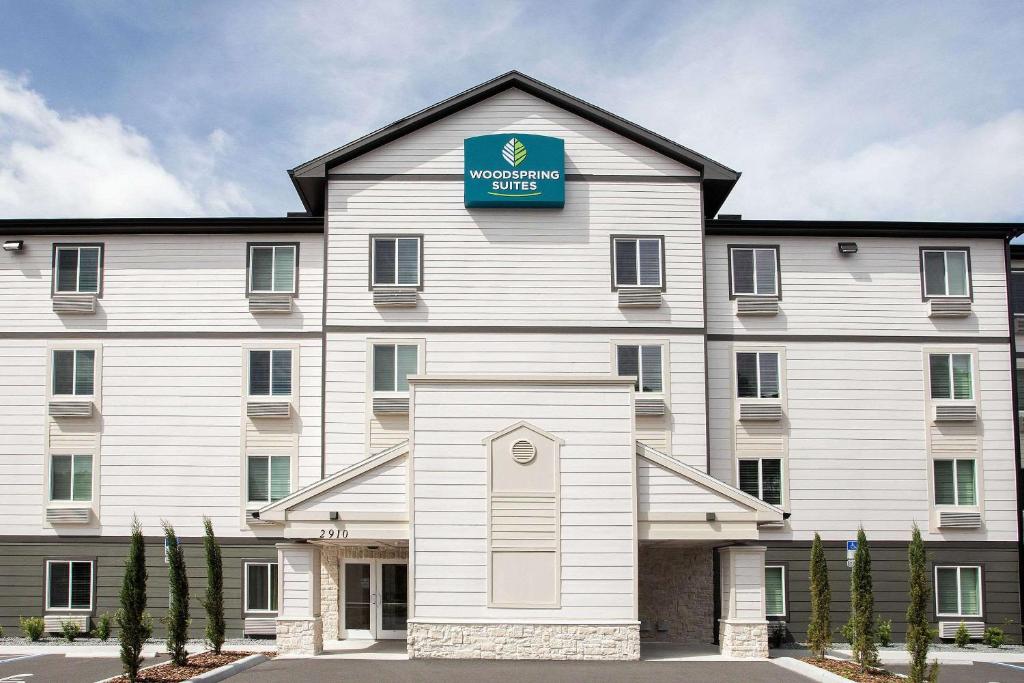 a large white building with a blue sign on it at WoodSpring Suites Daytona Beach Int'l Speedway in Daytona Beach