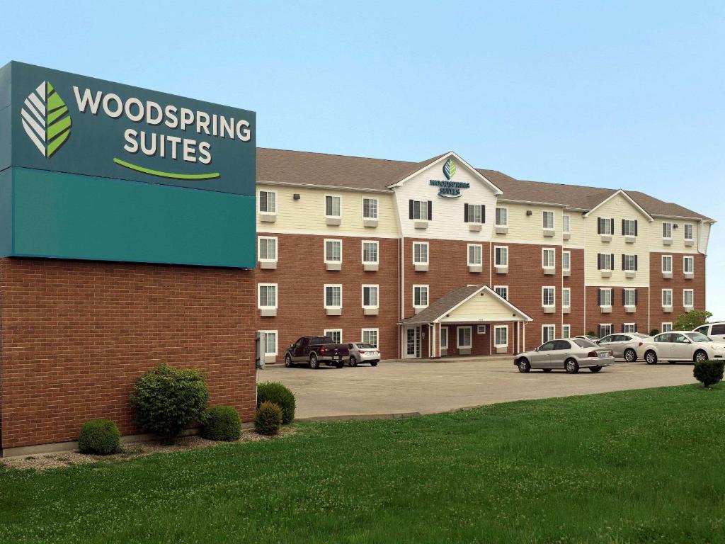 um sinal em frente a um edifício com carros num parque de estacionamento em WoodSpring Suites Louisville Clarksville em Clarksville