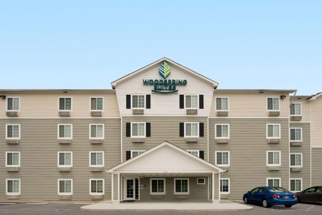 a large tan building with a sign on it at WoodSpring Suites Knoxville Airport in Alcoa