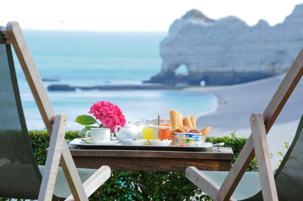 a tray of breakfast food on a table with a view of the ocean at Dormy House in Étretat