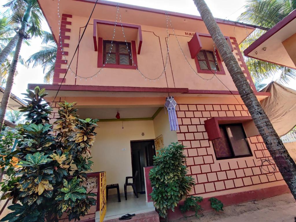 una casa rosa con palmeras delante en Shree Hari Guest House, en Anjuna