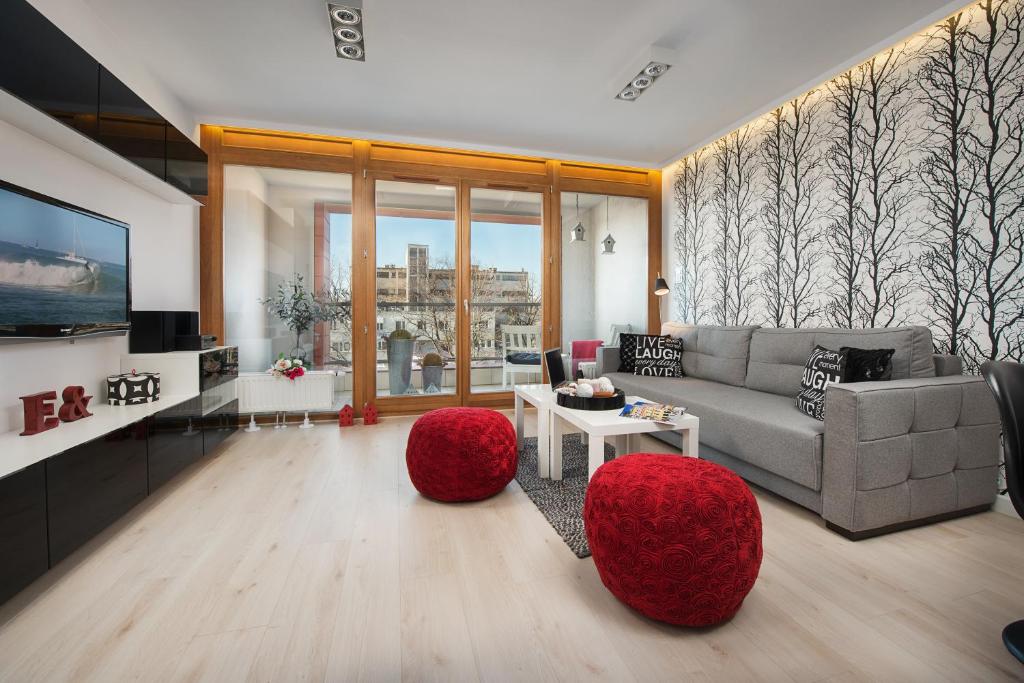 a living room with a couch and two red ottomans at Apartamenty Apartinfo Aura in Gdańsk