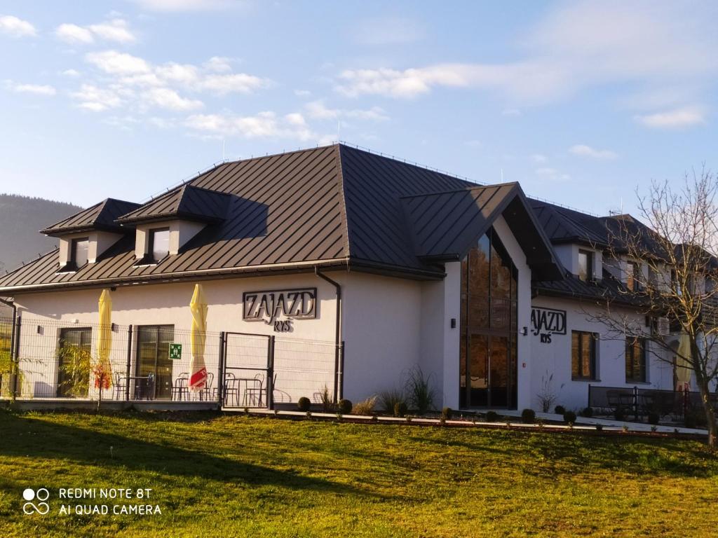 a large white house with a gambrel roof at Zajazd ,,RYŚ'' in Dobra