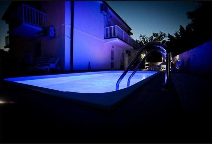 a swimming pool with a faucet in front of a house at Apartments Kalaba - Dalma II in Podaca
