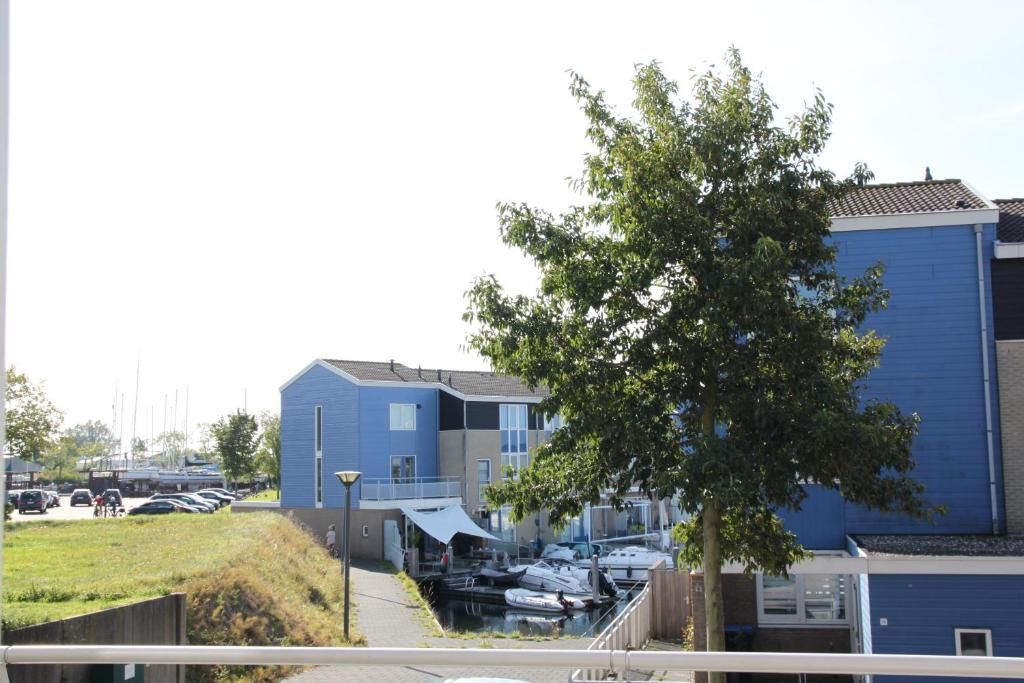 a blue building with a tree next to a marina at Vakantiehuis, Kaaidijk 42 Kortgene in Kortgene