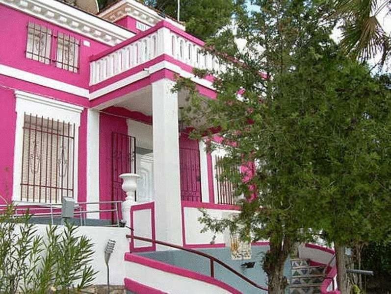 uma casa cor-de-rosa com uma árvore em frente em Villa Pachita em Alhama de Aragón