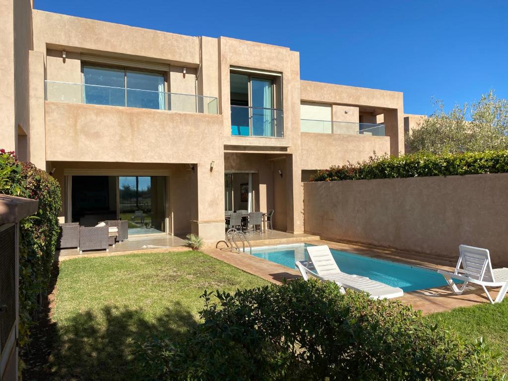 une maison avec une piscine et deux chaises longues dans l'établissement Villa prestige, à Marrakech