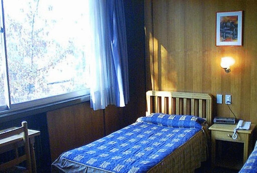 Habitación pequeña con cama y ventana en Posada del Salvador, en Santiago