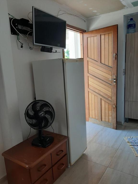 um quarto com uma televisão na parede e uma ventoinha em Quarto em Matinhos PR em Matinhos