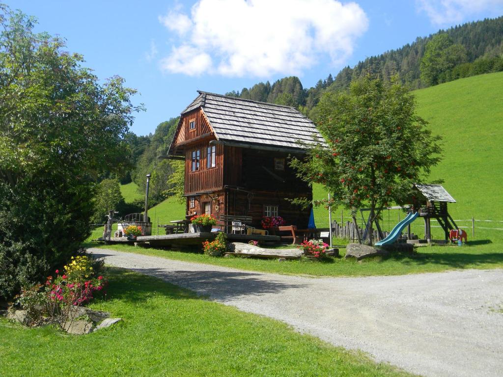 een houten huis met een speeltuin en een glijbaan bij Hüttenferien Köberlhof in Sankt Georgen ob Murau