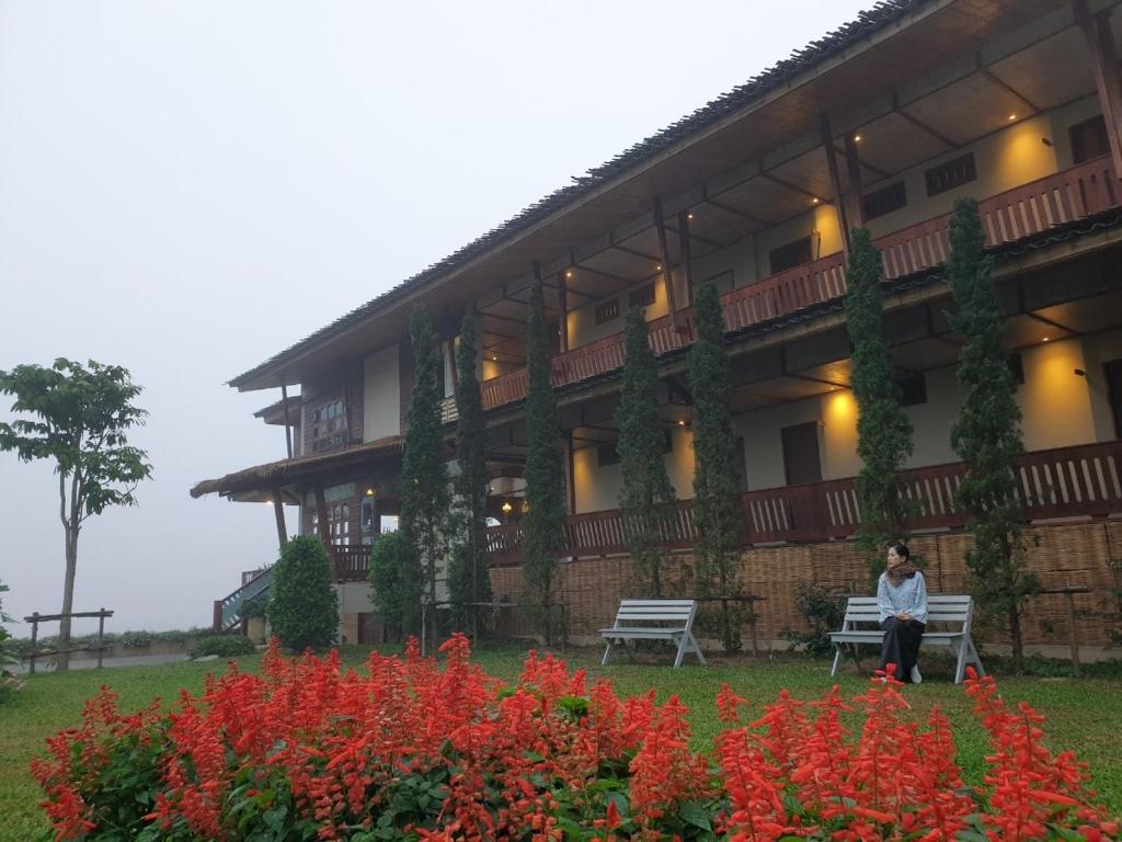 a woman sitting on a bench in front of a building at Sang Poy Cottage in Ban Kung Mai Sak