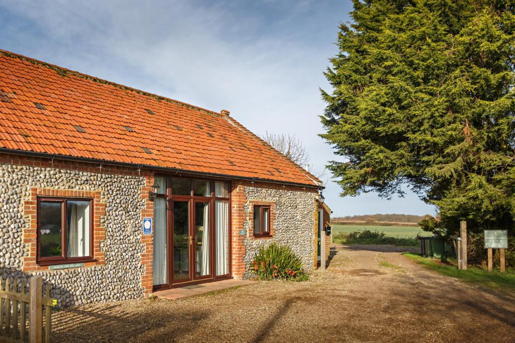 een stenen huis met een oranje dak op een onverharde weg bij The Barn in Felbrigg