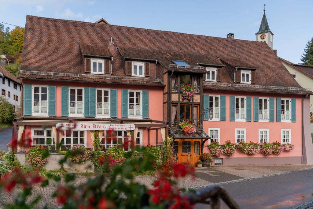 een roze en groen gebouw met bloemen ervoor bij Gasthaus-Pension Zum Kreuz in Stühlingen