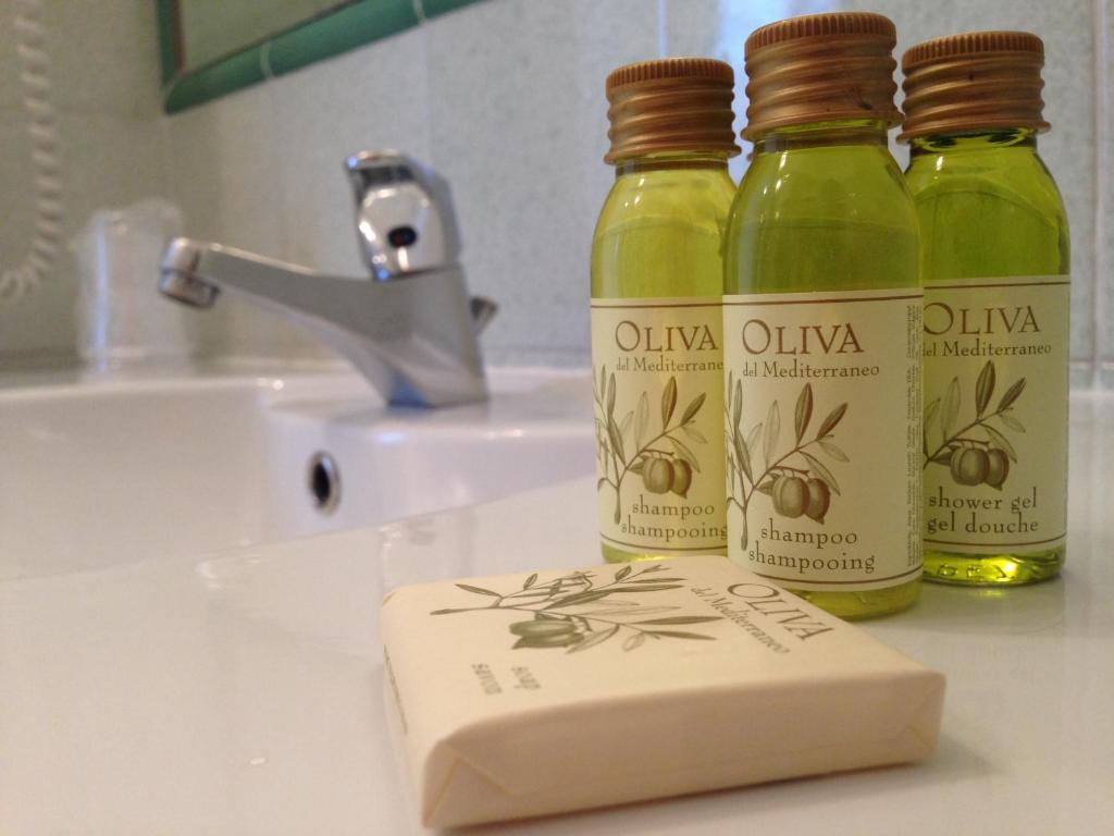 three bottles of olive oil sitting on a bathroom sink at Hotel Le Terrazze in Conca dei Marini