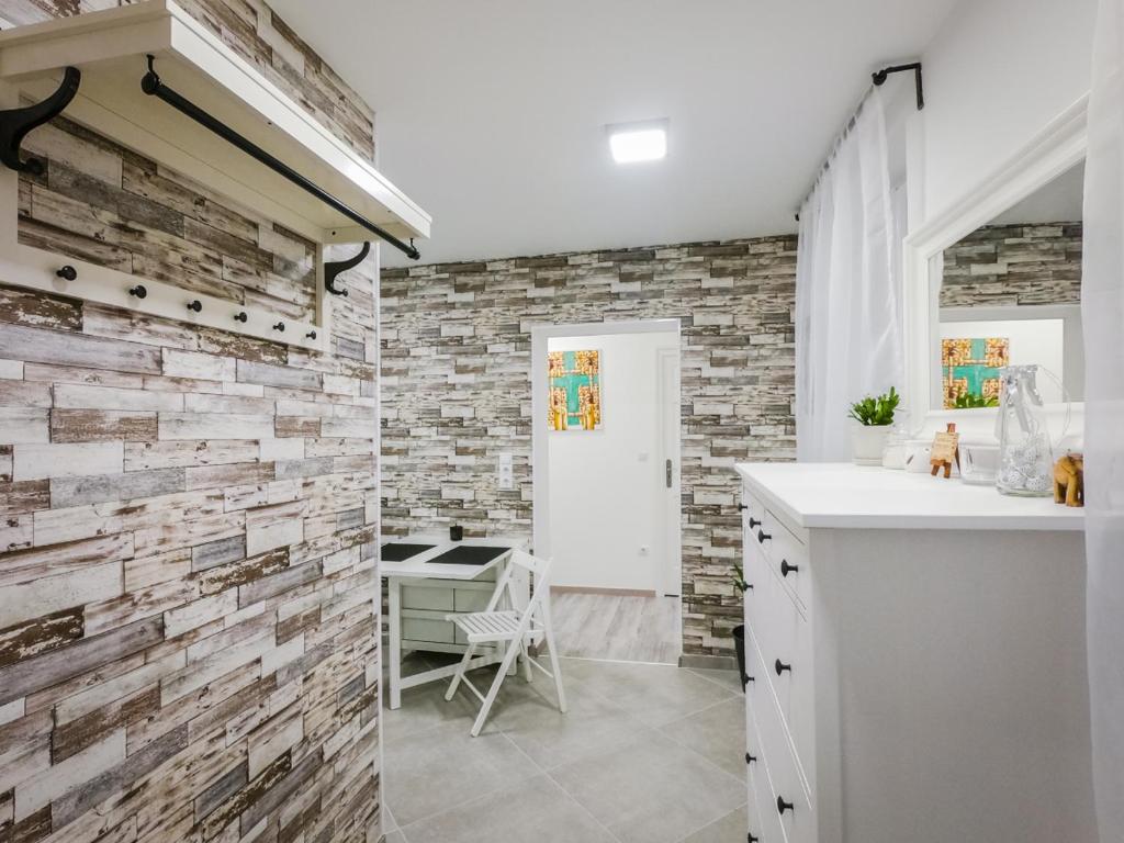 La salle de bains est pourvue d'un mur en pierre et d'un comptoir blanc. dans l'établissement Malasits Art Home, à Győr