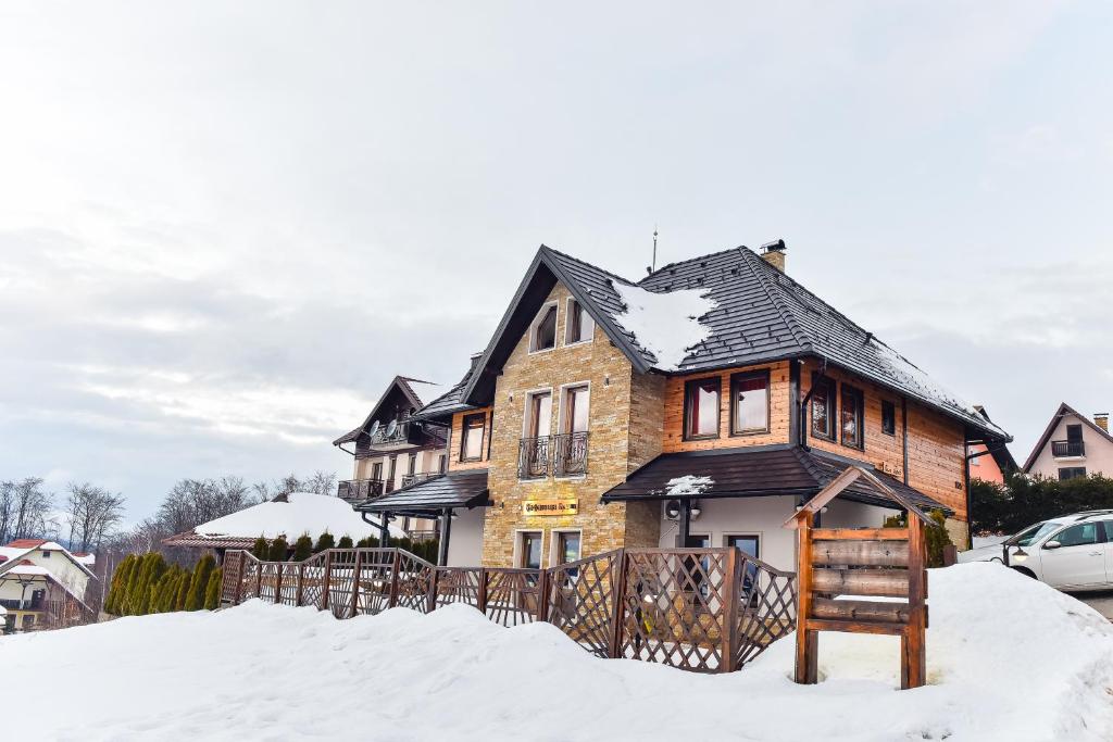 兹拉蒂博尔Vila Breg Zlatibor的雪中带黑色屋顶的房子