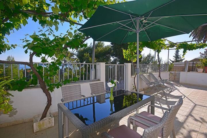 a patio with chairs and an umbrella and a pool at Apartments Dinka Miličić in Hvar