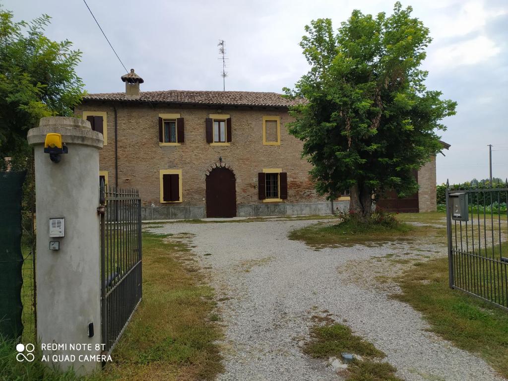 een oud huis met een poort en een boom bij La Rosa Selvatica in Ravarino