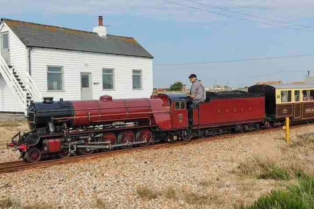 a man is standing on a red train on the tracks at Charming original fishermans cottage on Dungeness beach in Dungeness