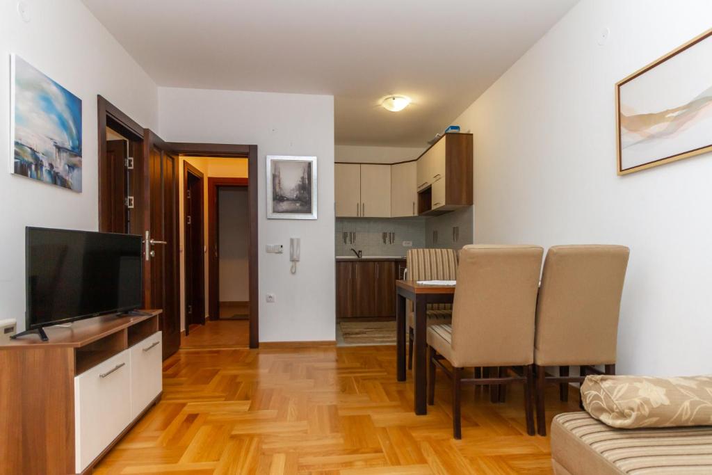 ein Wohnzimmer mit einem TV und einem Tisch mit Stühlen in der Unterkunft Apartman Nex in Zlatibor