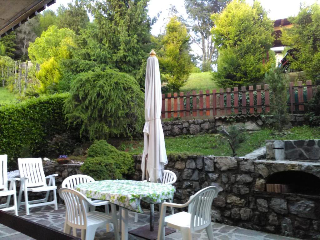 een patio met een tafel en stoelen en een parasol bij LA CASA DI PUFFY in Selvino