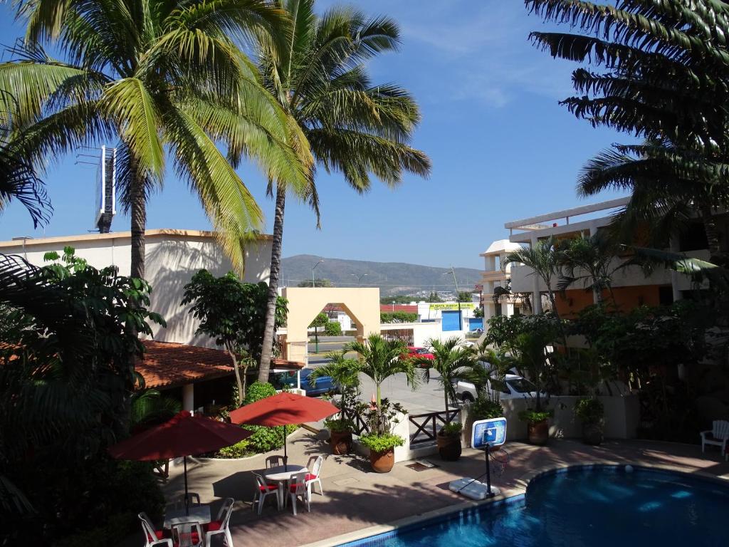 トゥストラ・グティエレスにあるHotel Palapa Palace Innのプールとヤシの木があるリゾートの景色を望めます。