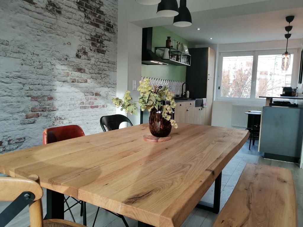 een houten tafel met een vaas met bloemen erop bij Maison avec garage, terrasse, l'Herboristerie in Béthune