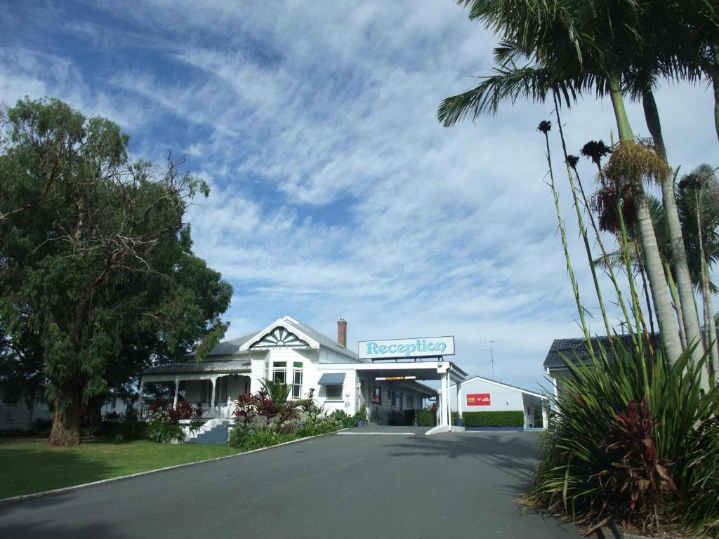 uma casa branca com uma placa numa rua em Colonial Court Motor Inn em Kempsey