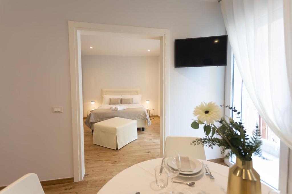 ein Schlafzimmer mit einem Bett und einem Tisch mit einer Blumenvase in der Unterkunft Ca' Benedetta ApartSuite House in Sottomarina