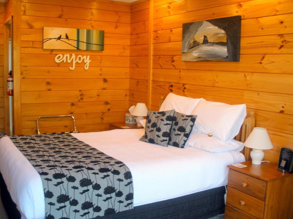 a bedroom with a bed and a wooden wall at Andrea's Bed & Breakfast in Whitianga